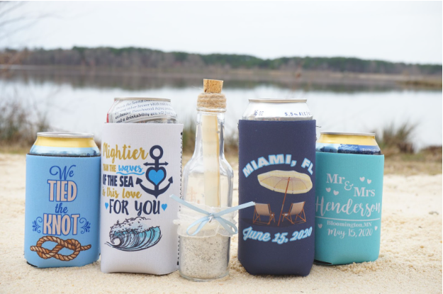 Custom beach wedding koozies with a navy, white, and gold color scheme featuring nautical symbols.