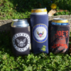 Three custom koozies with "Joe's Navy" written on them, designed to hold cans