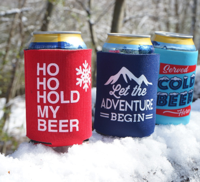 a group of custom can winter koozies in the snow